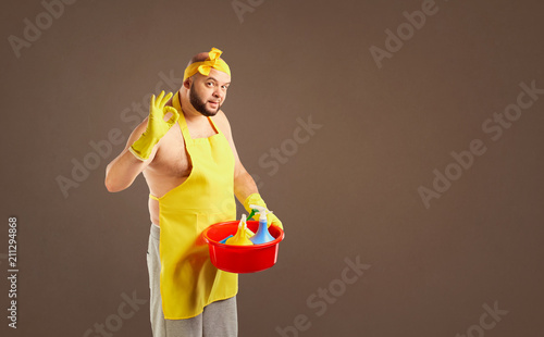 Funny fat cleaning man in an apron on cleaning on a background for text.