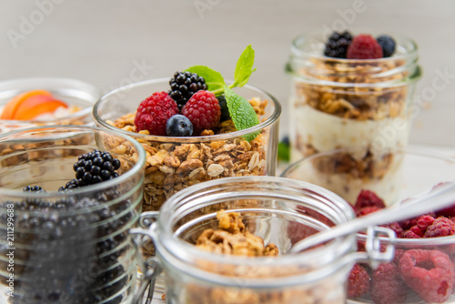 Jars full with granola, yogurt and fresh berries, close-up, selective focus