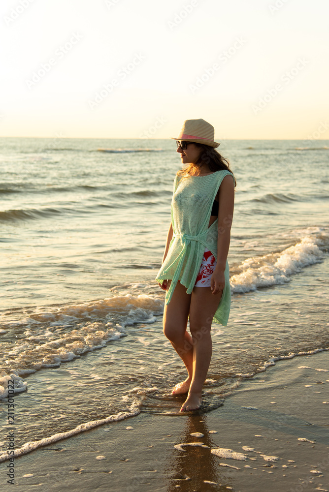 A girl on the beach at the sunrise, admiring and enjoying the sea breeze