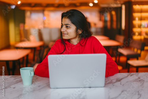 Young attractive Indian student working with a laptop and enjoying a coffee  © Danon