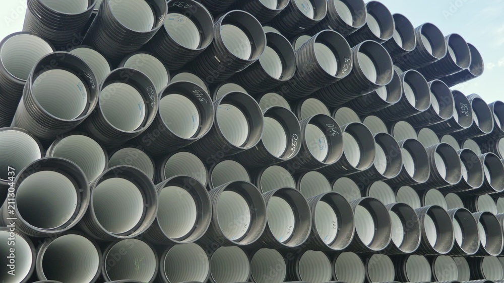 Warehouse of finished plastic pipes industrial outdoors storage site. Manufacture of plastic water pipes factory. Process of making plastic tubes on the machine tool with the use of water and air Warehouse of finished plastic pipes industrial outdoors storage site. Manufacture of plastic water pipes factory. Process of making plastic tubes on the machine tool with the use of water and air
