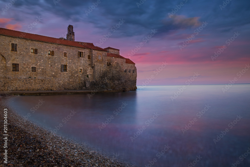 Ancient castle on the beach at sunset with colorful sky reflecting in the water
