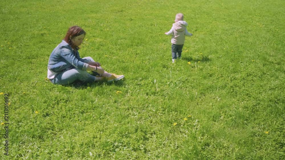 Mom and little toddler are playing on green grass of park Mom and little toddler are playing on green grass of park