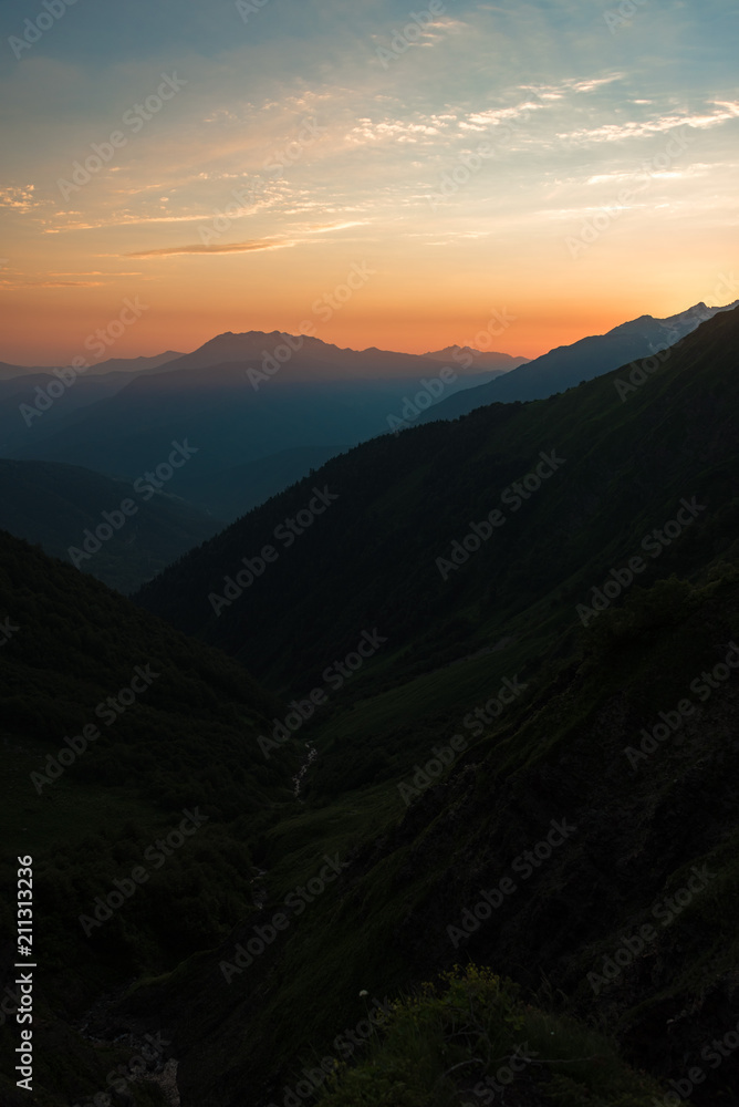 Sunset high in the mountains. Peaks of high mountains and golden clouds in the sky. Evening landscape. Sunset high in the mountains. Peaks of high mountains and golden clouds in the sky. Evening landscape.