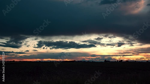 Time lapse of colorful sunset over farm field in Idaho as sun burst fades behind clouds. photo