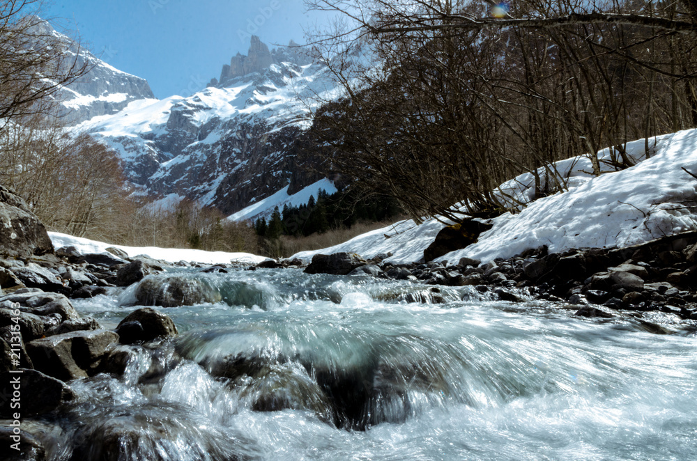 Fototapeta premium Mountain cold ice creek stream flowing rapidly in high mountains covered with stone