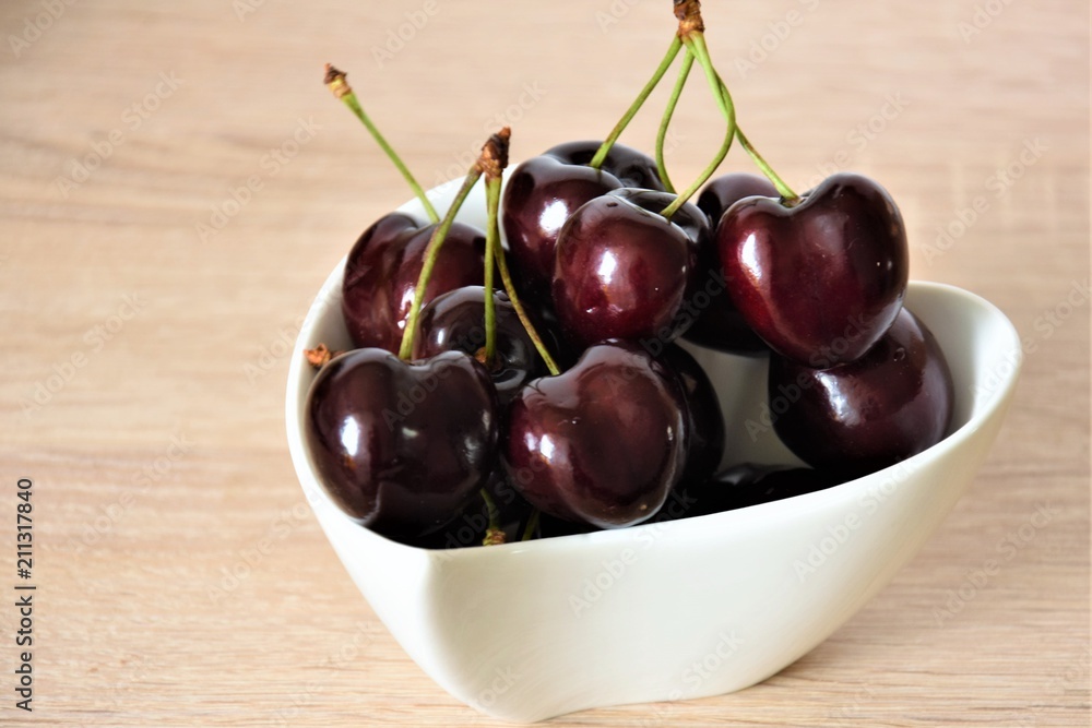 ripe large cherry in a white cup on a wooden table ripe large cherry in a white cup on a wooden table