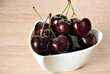 ripe large cherry in a white cup on a wooden table