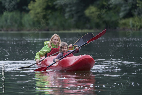 Mom and daughter fun and amicably manage a canoe boat on a wide river.