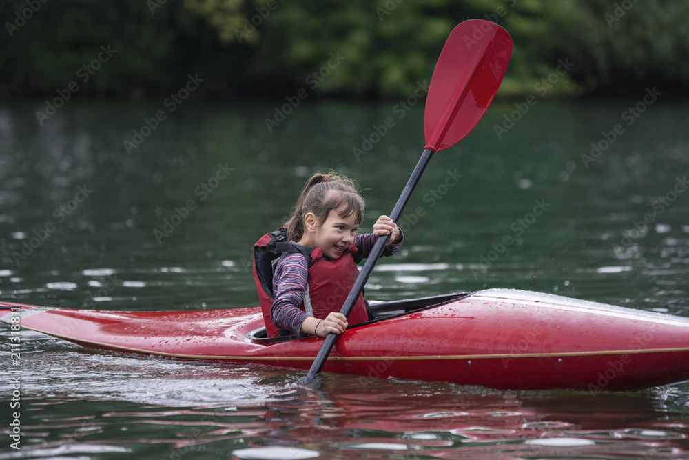 young teenager girl actively manages a sports kayak boat on a beautiful river.
