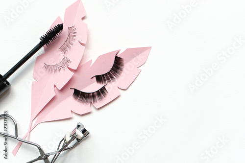 Fotografija Black false lashes strips, mascara, curler  on white background