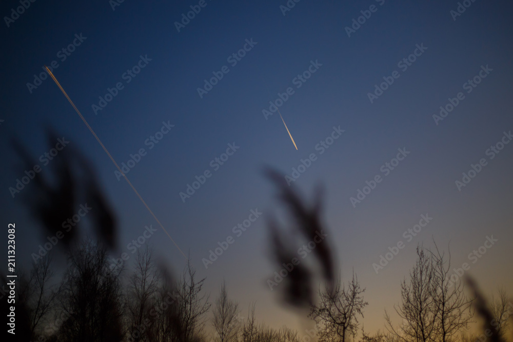 Obraz premium Airplane flying in the sky among clouds and sunset