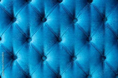 Coach-type velours screed tightened with buttons. Blue chesterfield style quilted upholstery backdrop close up. texture background