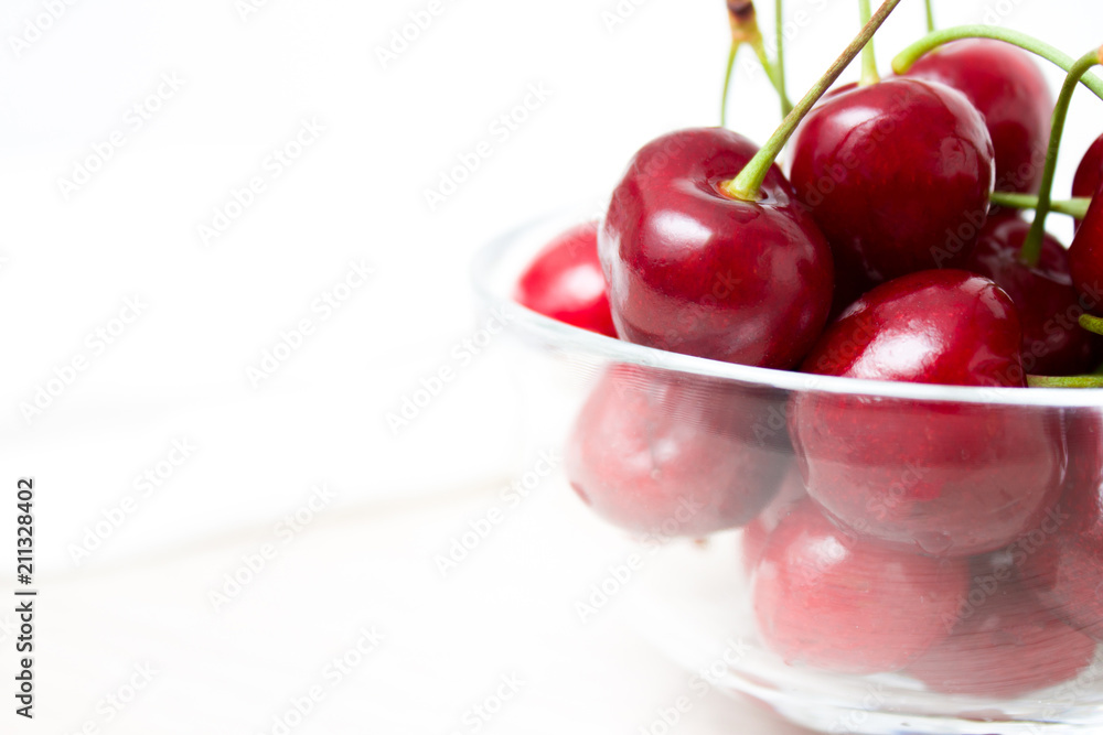 Cherries in glass dish. Cherry on wood and white background. - healthy eating and food concept