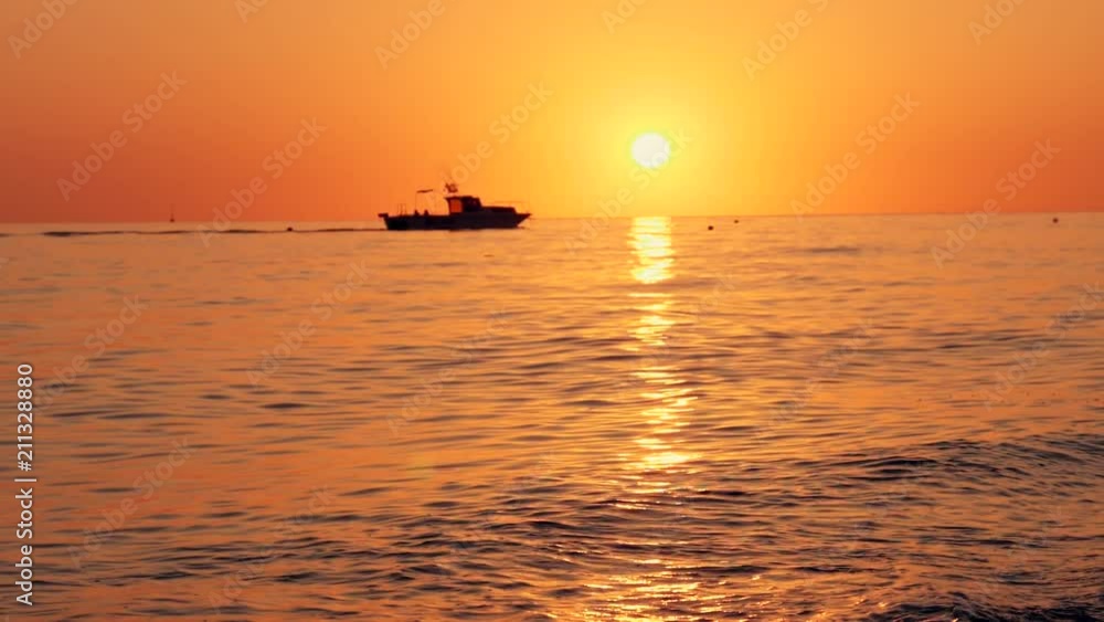 Beautiful sunset. The ship sails the waves during sunset. Sea walk on a sea ship. Silhouette of the ship at sunset. Beautiful sunset. The ship sails the waves during sunset. Sea walk on a sea ship. Silhouette of the ship at sunset.