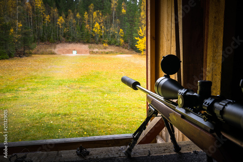 Fotografie Sniper rifle with silencer and scope at shooting range