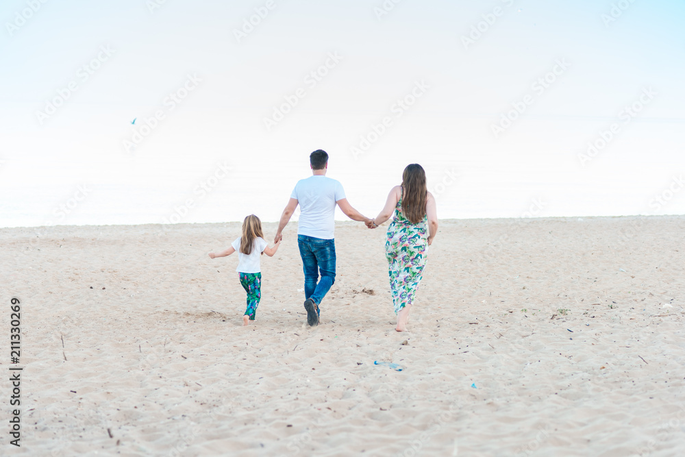 Portrait of young family walking along beach