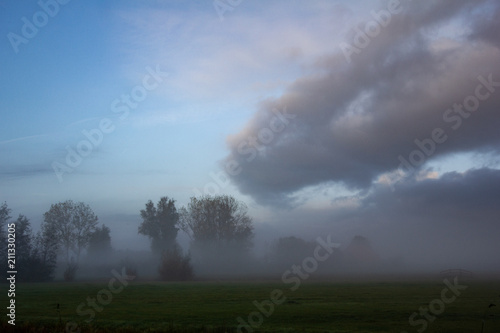 View of nature in misty morning in Friesland province with amazing cloudscape on the sky