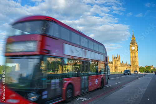 Blurry red bus in motion and Big Ben in the background in London. England
