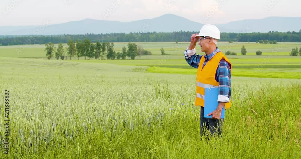 Engineer Analyzing Checklist On Clipboard Amidst Crops At Farm Engineer Analyzing Checklist On Clipboard Amidst Crops At Farm