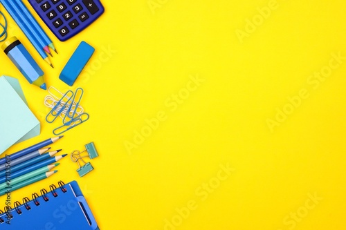 Blue school supplies side border against a bright yellow paper background