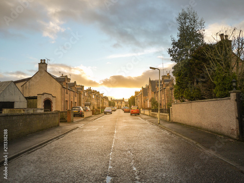 A road leads to a quiet residential neighbourhood area with traditional British style houses during sunset. Inverness, Scotland, United kingdom photo