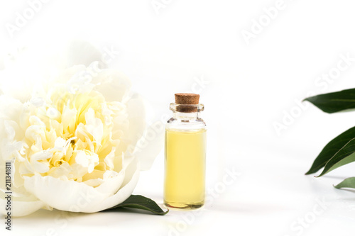White peony flower and bottle with oil or essence on white. Close up.