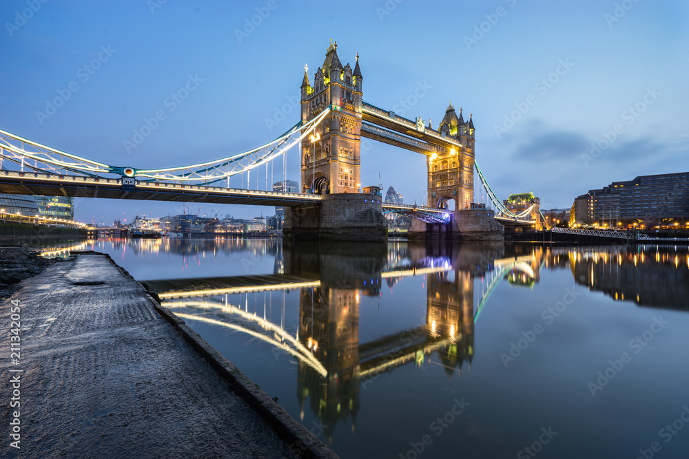 Tower Bridge with blue sky and with beautiful water reflection during low tide in London, England