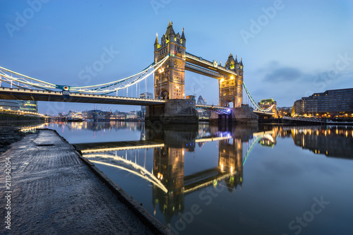 Tower Bridge with blue sky and with beautiful water reflection during low tide in London, England