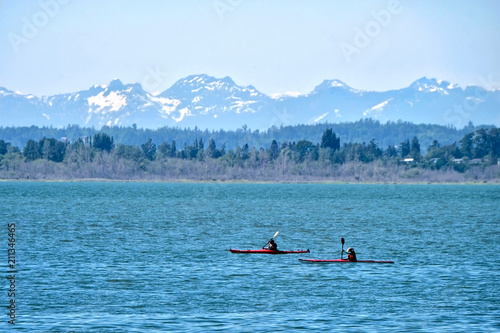 Sea kayaks in water. Kayaking in Pacific Ocean with scenic view of snow capped mountains in Olympic Peninsula. Seattle. Washington State. United States of America.