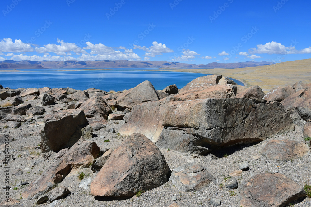 China. Great lakes of Tibet. Stones with mantras on the store of Lake Teri Tashi Namtso in sunny summer day China. Great lakes of Tibet. Stones with mantras on the store of Lake Teri Tashi Namtso in sunny summer day