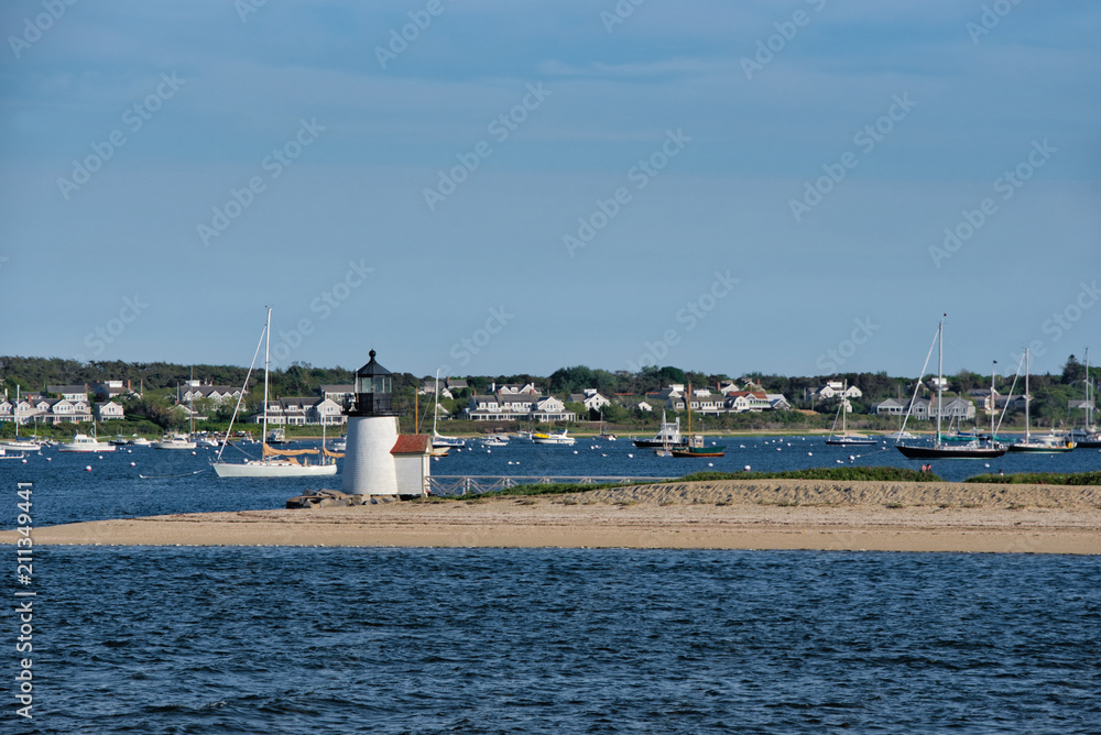 Brant Point lighthouse juts out into the harbor of Nantucket Island on a sunny, summer day