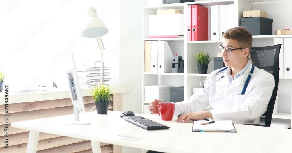 Young doctor drinking coffee in workplace. Young doctor drinking coffee in workplace.