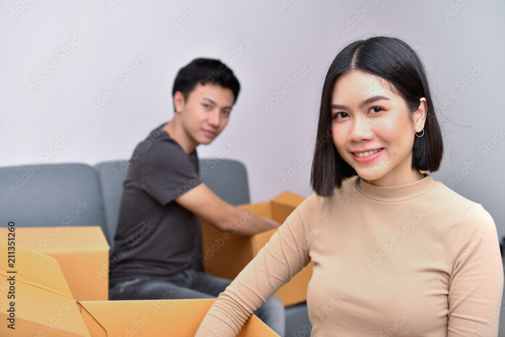 Moving house Concept. Asian young man is carrying his belongings. Young Asian women are holding their stuff in a paper box. Young are happy in the new house. Moving house Concept. Asian young man is carrying his belongings. Young Asian women are holding their stuff in a paper box. Young are happy in the new house.