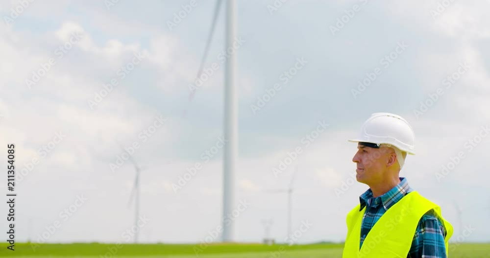Smiling Engineer Using Digital Tablet At Windmill Farm Against Sky Smiling Engineer Using Digital Tablet At Windmill Farm Against Sky
