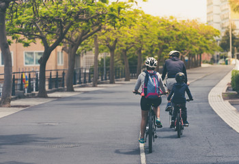 Family are riding on bikes at bicycle path. Photography with vintage filter.