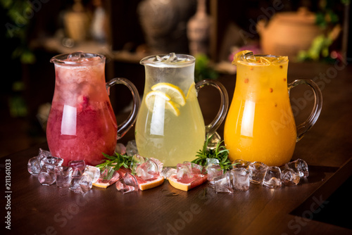 Delicious set of refreshing summer drinks on wooden background with ice pieces