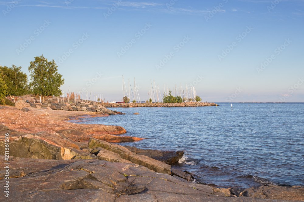 View of empty cliff, ocean and sailing boats' masts in Helsinki, Finland, on a sunny afternoon in the summer. Copy space.