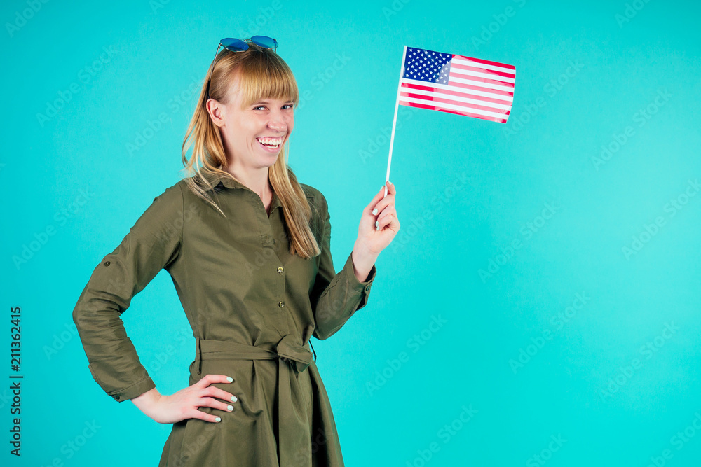 young and active blonde woman holds American flag in studio on blue background young and active blonde woman holds American flag in studio on blue background