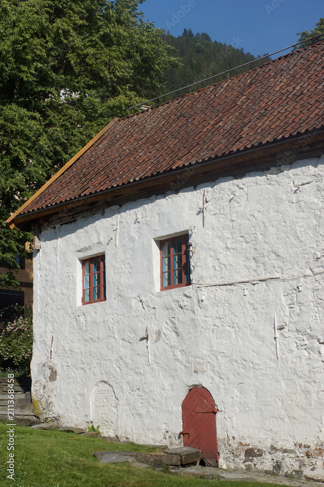 A small house with white walls and small windows and a door in Bergen in Norway. A small house with white walls and small windows and a door in Bergen in Norway.