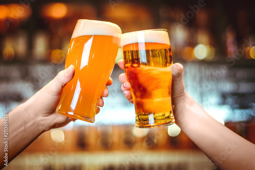 Two friends toasting with glasses of light beer at the pub. Beautiful background of the Oktoberfest. fine grain. Soft focus. Shallow DOF