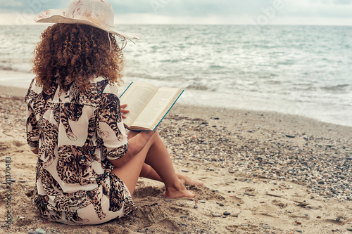 Foto Woman portrait sitting near the sea and reading book on Summer vacations
