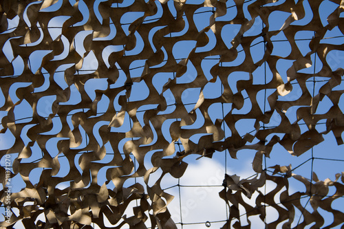 war signs. Detail of a beige camouflage grid paper, on the bottom blue sky