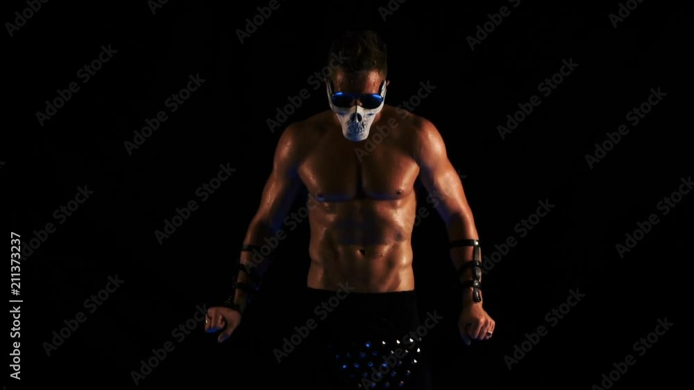 Man in a mask of a skull and glasses dance on black background Man in a mask of a skull and glasses dance on black background