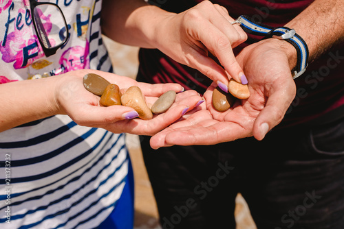 Hands of a couple shining stones on the beach