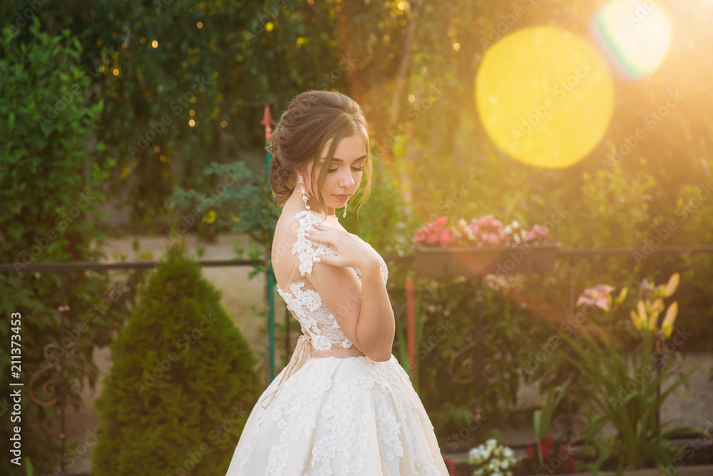 Young girl in wedding dress in park posing for photographer Young girl in wedding dress in park posing for photographer