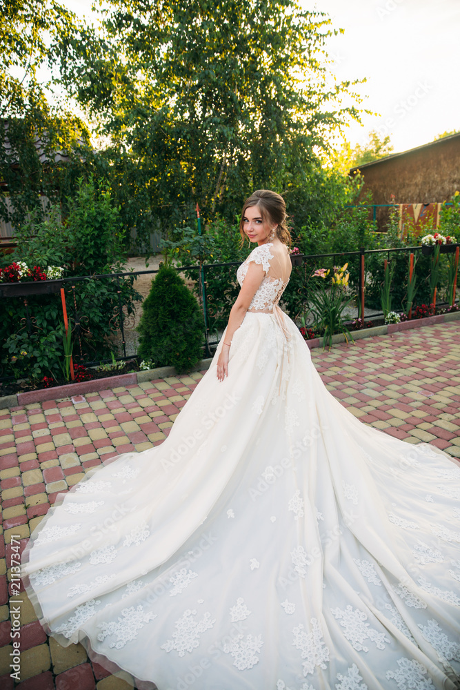 Fototapeta premium Young girl in wedding dress in park posing for photographer