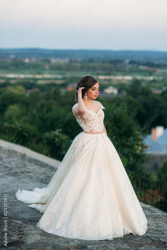 Teenage girl in wedding dress on city. Background town sunset Teenage girl in wedding dress on city. Background town sunset