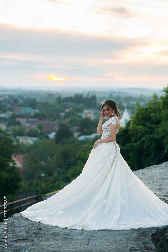 Teenage girl in wedding dress on city. Background town sunset Teenage girl in wedding dress on city. Background town sunset