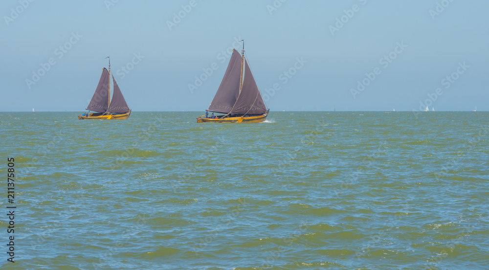 Obraz premium Sailboats sailing in a lake below a blue sky in summer